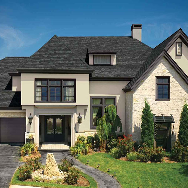 Front view of residential home with beige siding and charcoal black GAF shingles on its roof